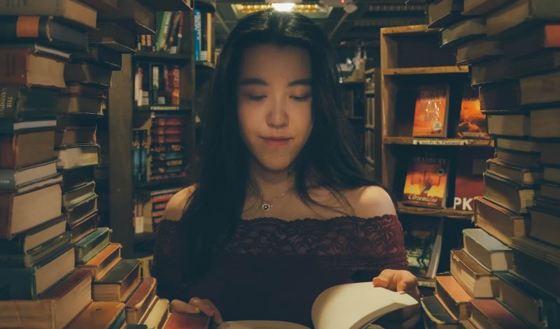Eine Frau liest ein Buch in einer Mauer aus Büchern